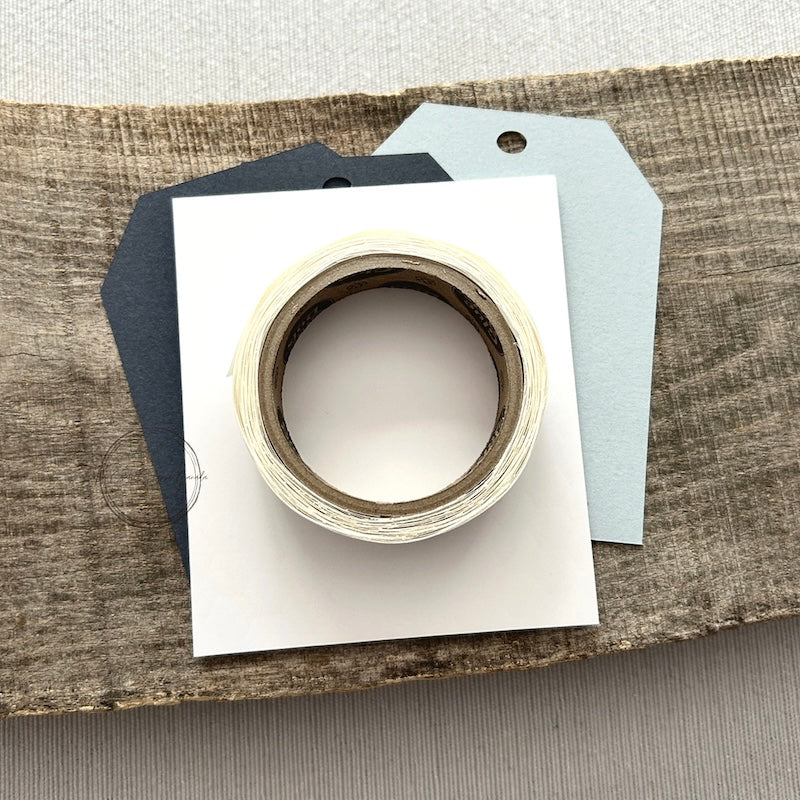 A roll of glue dots and a sheet of pop dots are sitting on a few blank tags. They are included in your gift tag kit.