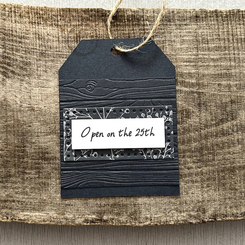 A finished tag, from this gift tag kit, sitting on a wooden board.