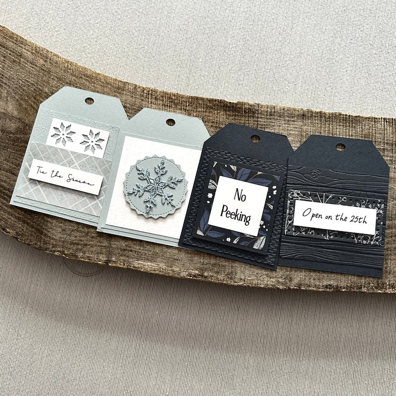 There are 4 finished tags, sitting on a wooden board, to show the finished tags that are included in this kit.
