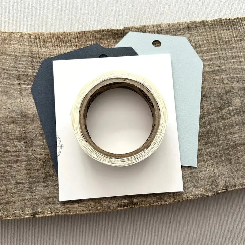 A roll of glue dots and a sheet of pop dots are sitting on a few blank tags. They are included in your gift tag kit.