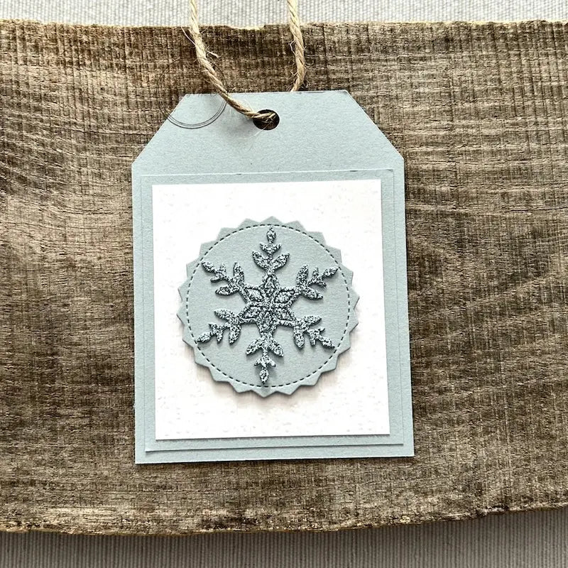 A finished tag, from this gift tag kit, sitting on a wooden board.