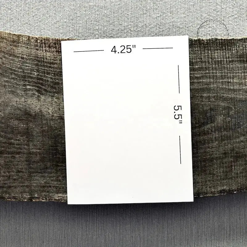 A blank card is sitting on a wooden board to show the measurements of the 4.25" x 5.5" card.