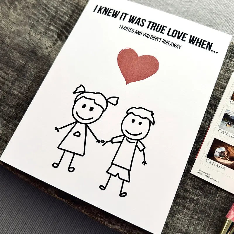 The printable greeting card is sitting on a wooden board with a pen and stamps.