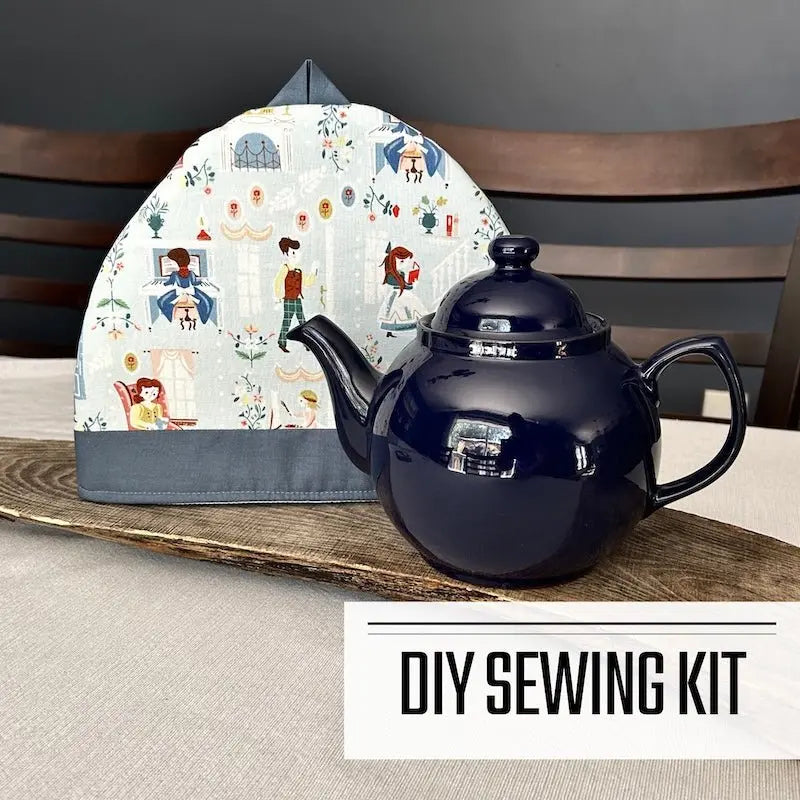 A DIY sewing kit for a teapot cozy. The finished cozy is sitting on a wooden board, beside a blue teapot.