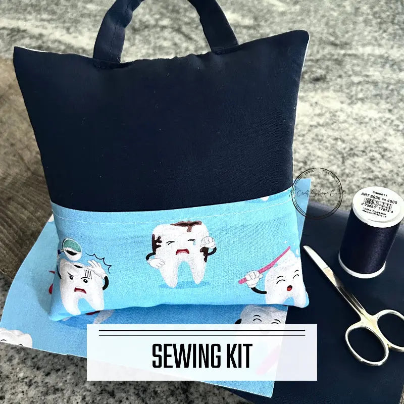 A DIY sewing kit for a tooth fairy pillow. The 2 pillows are lying on a wooden board on a counter.