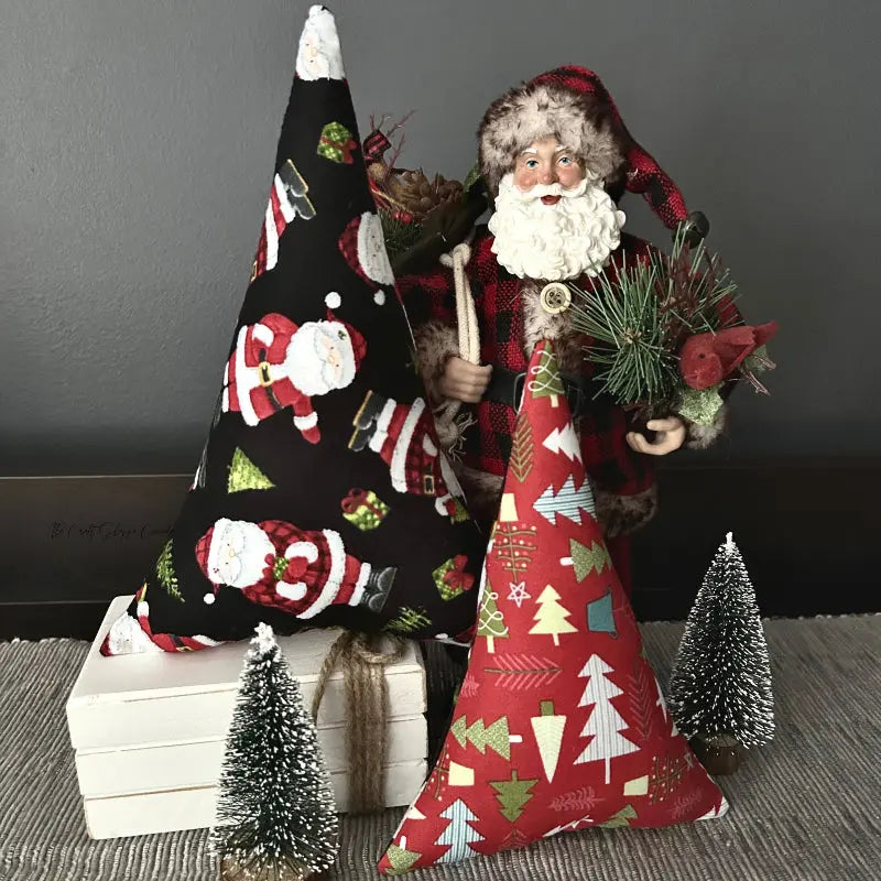 The 2 Christmas trees, made from this sewing pattern, are sitting on top of a dining room buffet with a Santa behind them.
