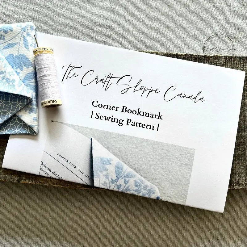 The pattern is lying on a wooden board with fabric, a spool of thread and a hand sewing needle.