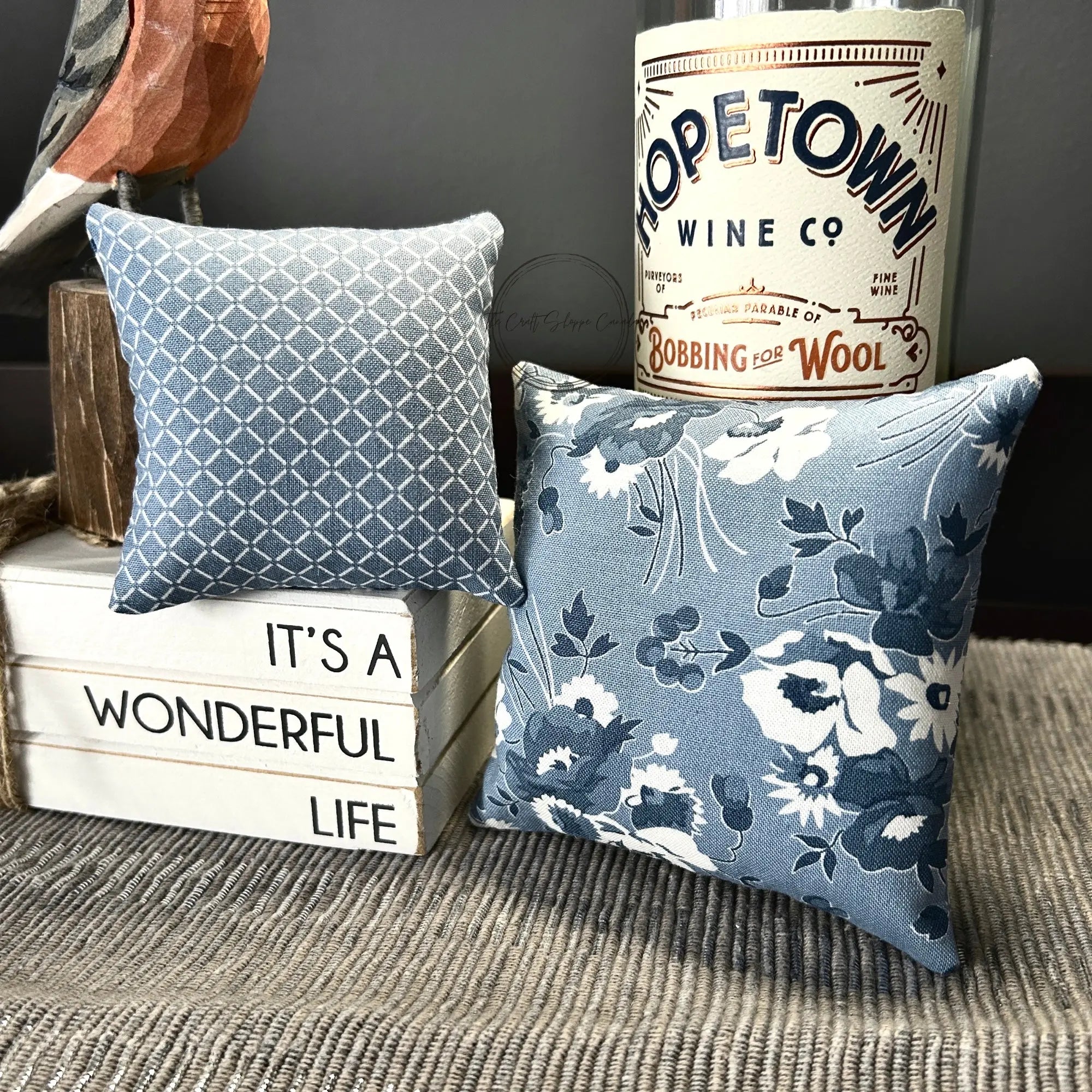 The finished pin cushions, made from this sewing pattern, are sitting on a buffet with decor items.