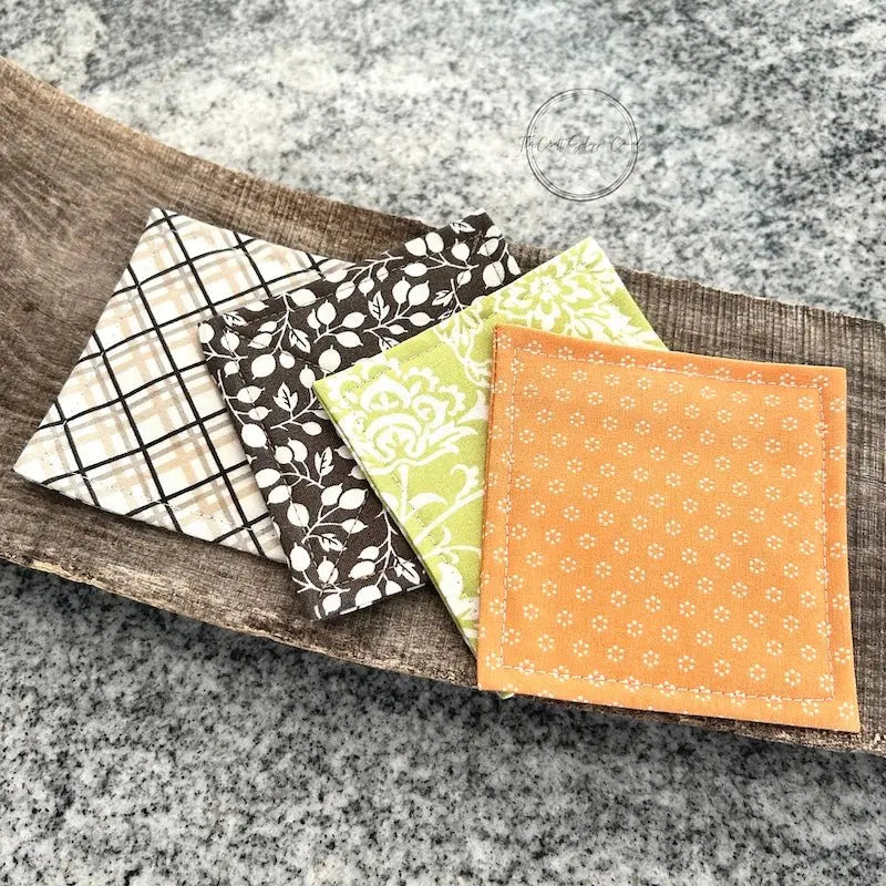 The finished coaster set, made from this sewing pattern, lying on a wooden board.
