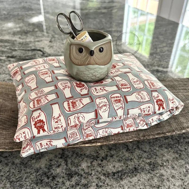 The rice bag heading pad, made from this sewing pattern, is folded on top of a wooden board.