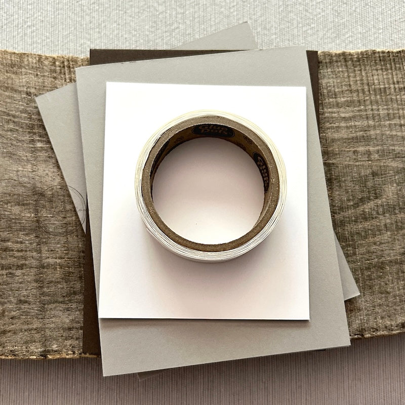 A roll of glue dots and a sheet of pop dots are sitting on a few blank cards. They are included in your card making kit.