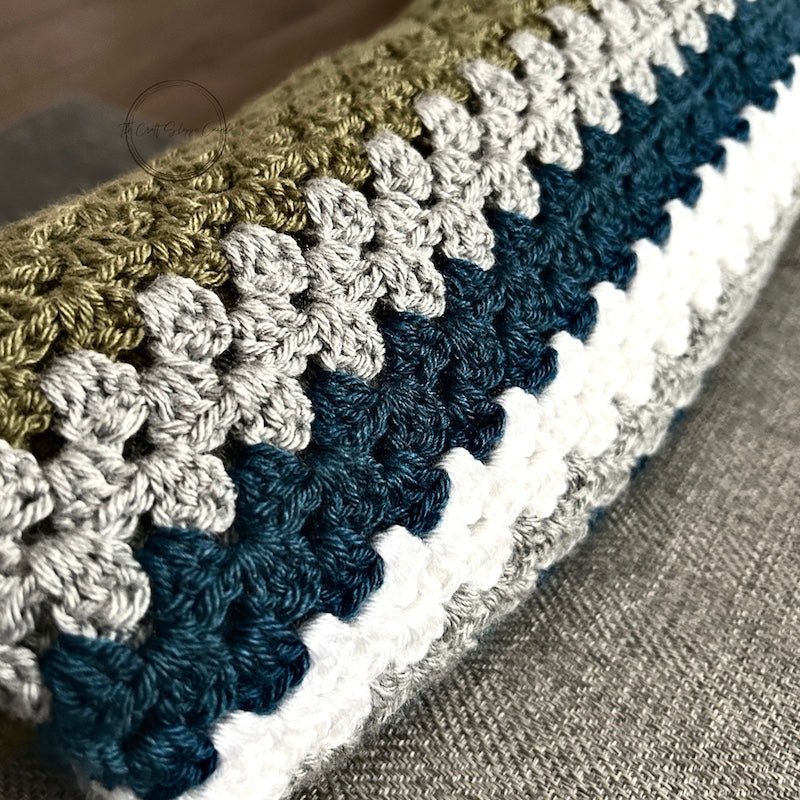 The finished green, teal and grey blanket folded up to show the granny square stitches - The Craft Shoppe Canada