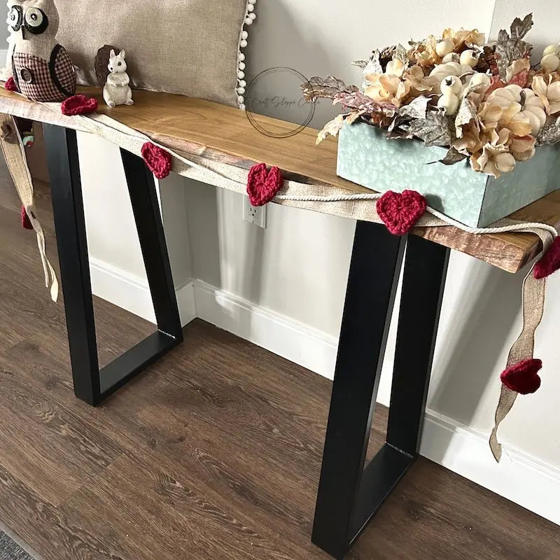 A look at the finished heart garland, made from this crochet pattern, hanging over a table.