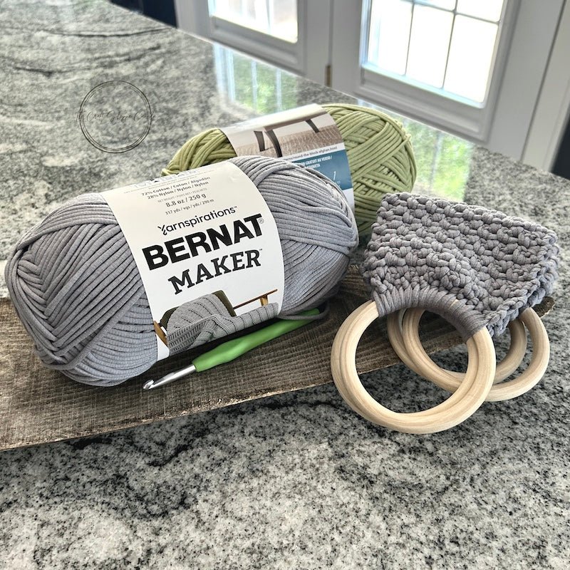 The completed towel holders folded on a wood board with yarn and a crochet hook - The Craft Shoppe Canada
