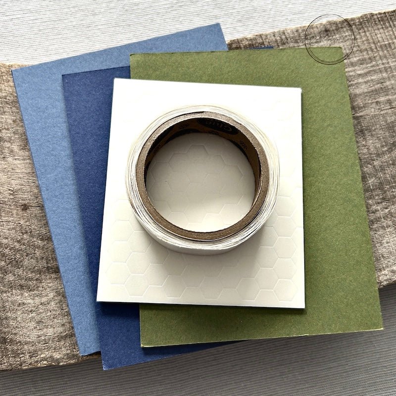 A roll of glue dots and a sheet of pop dots are sitting on a few blank cards. They are included in your DIY card kit - The Craft Shoppe Canada