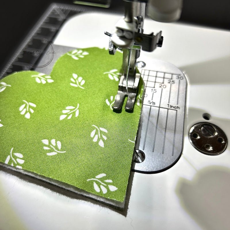 A green heart under a sewing machine ready to to be sewn - The Craft Shoppe Canada