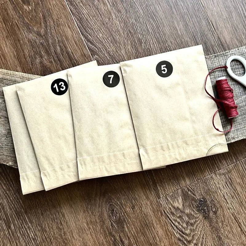 A few of the card kits from the Advent calendar are lying on a wooden board with twine.