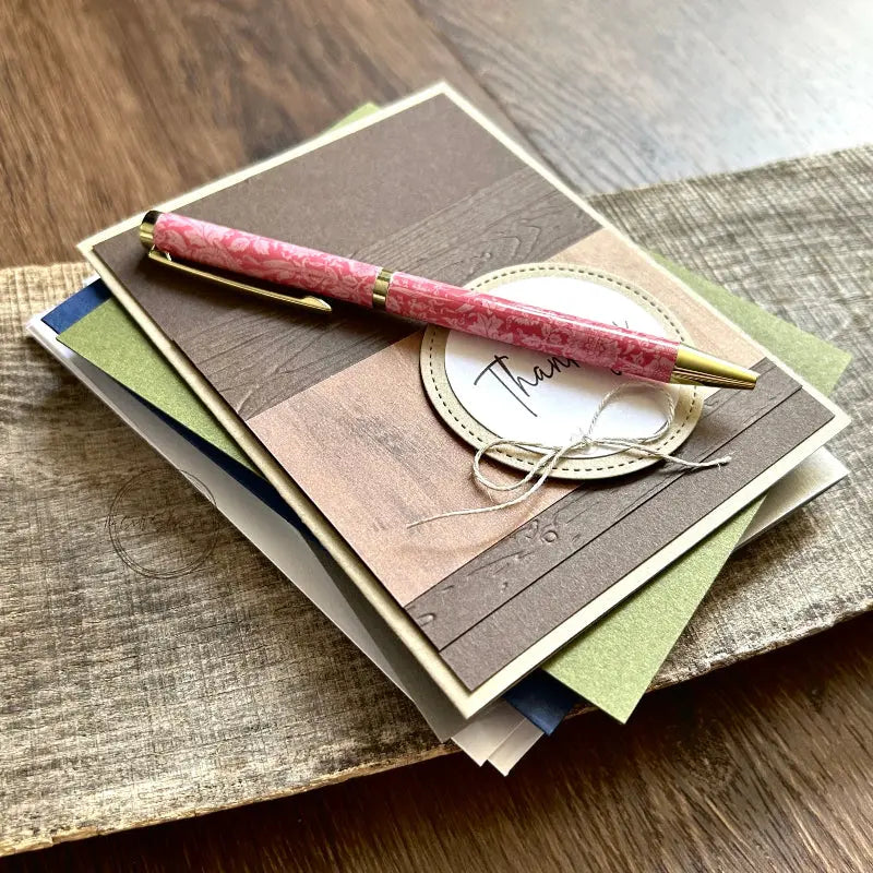 Some of the finished card, from this card making kit, are sitting on a wooden board with a pen.