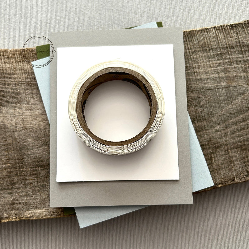 A roll of glue dots and a sheet of pop dots are sitting on a few blank cards. They are included in your card making kit.