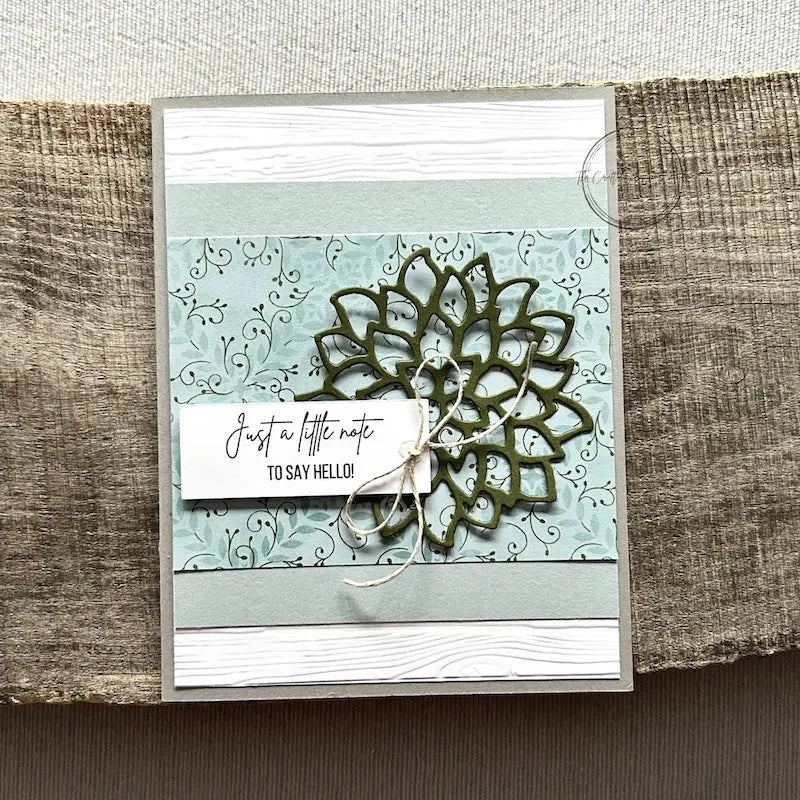 A finished card, from this card making kit, sitting on a wooden board.