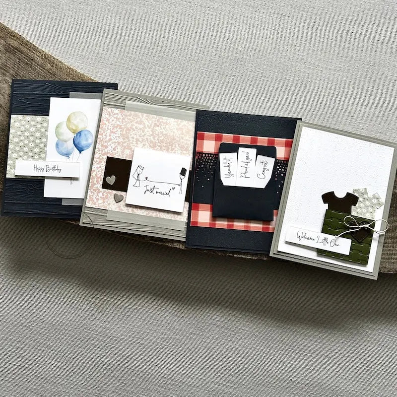 There are 4 finished cards, sitting on a wooden board, to show the finished cards that are included in this card making kit.