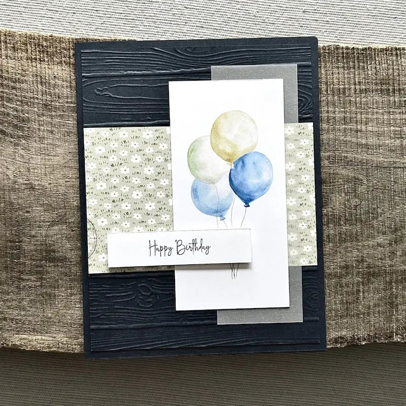 A finished card, from this card making kit, sitting on a wooden board.