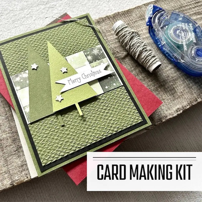 A DIY card making kit for Christmas. A finished card is sitting on blank cards with a roll of twine and a tape runner.