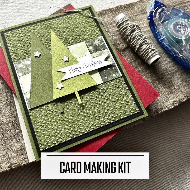A DIY card making kit for Christmas. A finished card is sitting on blank cards with a roll of twine and a tape runner.