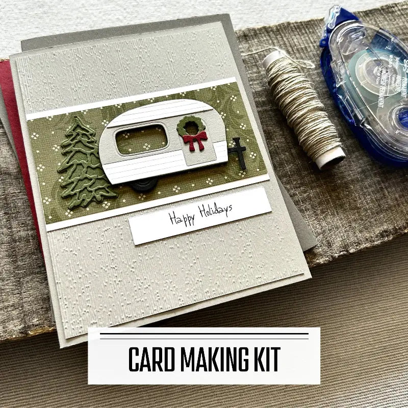 A DIY card making kit for Christmas. A finished card is sitting on blank cards with a roll of twine and a tape runner.