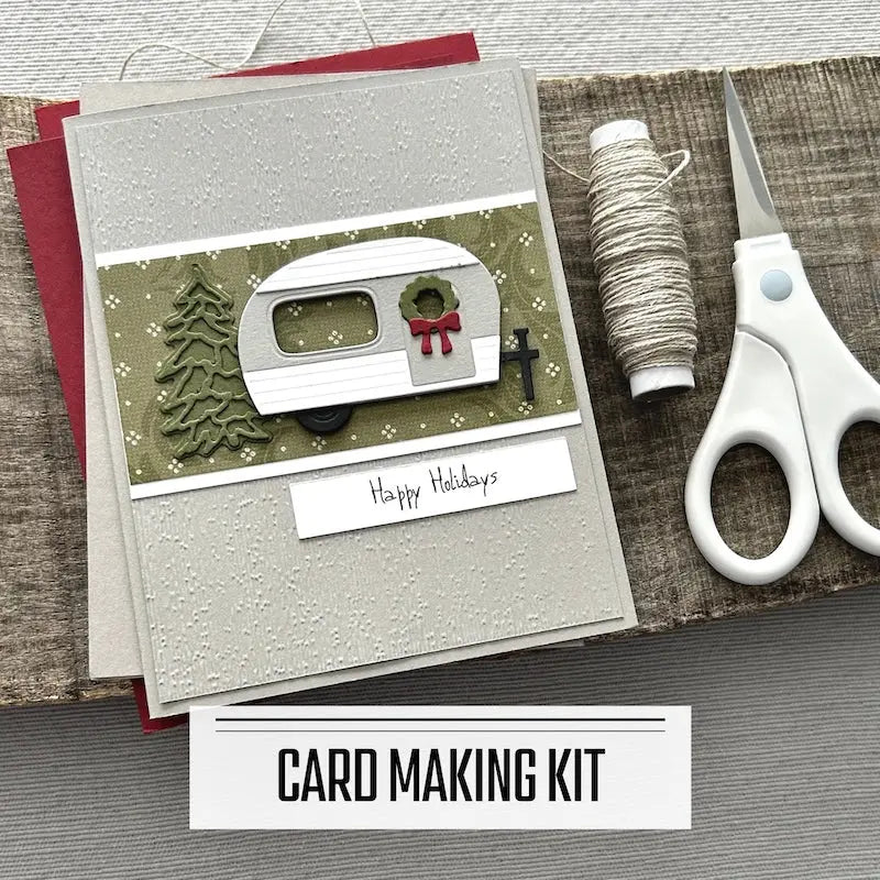 A DIY card making kit for Christmas. A finished card is sitting on blank cards with a roll of twine and scissors.