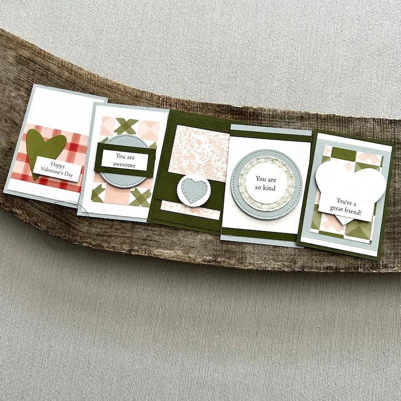 There are 5 finished valentines, sitting on a wooden board, to show the finished cards that are included in this kit.