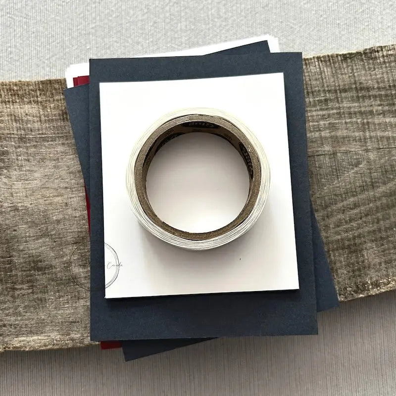 A roll of glue dots and a sheet of pop dots are sitting on a few blank cards. They are included in your card making kit.