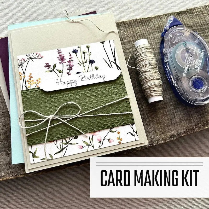 A DIY card making kit for Birthday cards. A finished card is sitting on blank cards with a roll of twine and a tape runner.