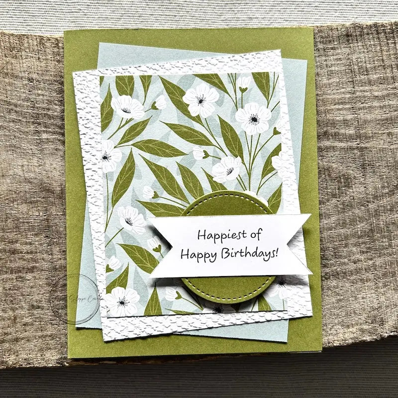 A finished card, from this card making kit, sitting on a wooden board.