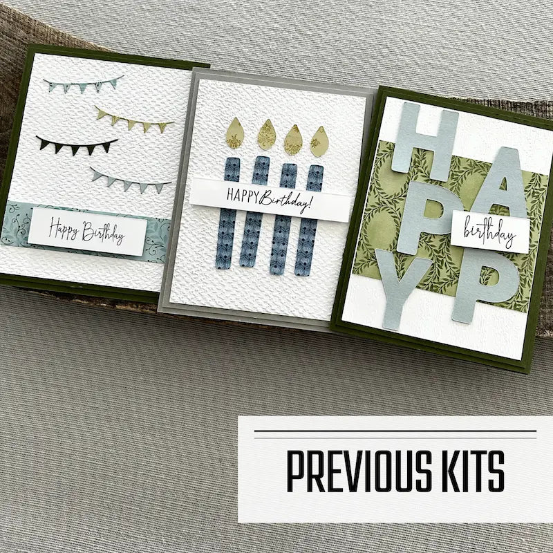 There are 3 finished cards, sitting on a wooden board, to show what cards have been sent in previous kits.