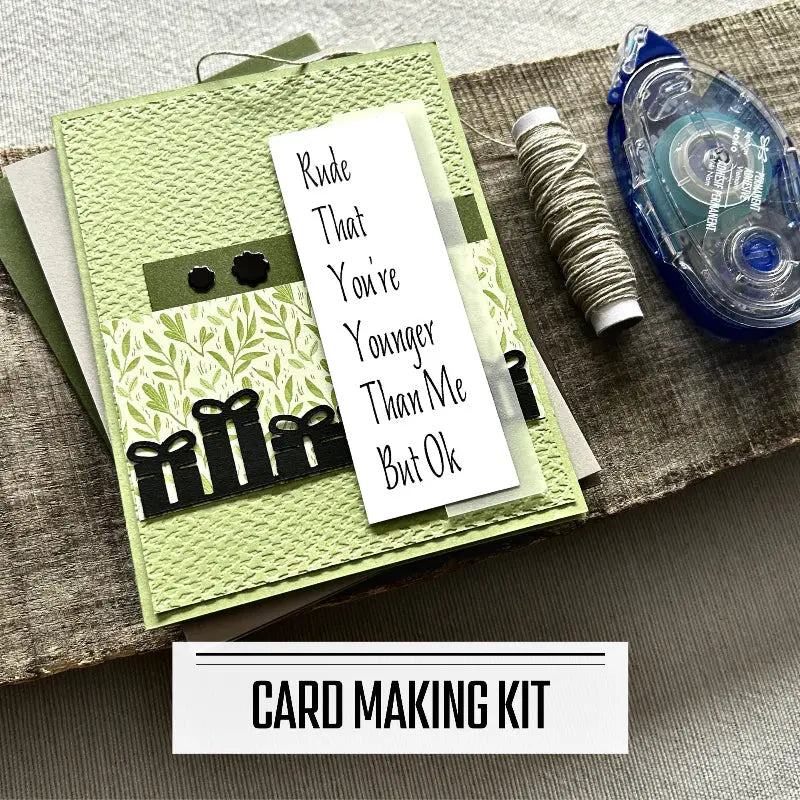 A DIY card making kit for cards with sarcastic and funny sentiments. A finished card is sitting on blank cards with a roll of twine and a tape runner.