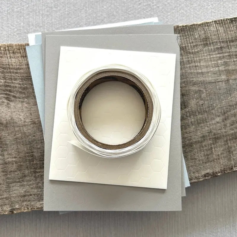 A roll of glue dots and a sheet of pop dots are sitting on a few blank cards. They are included in your card making kit.