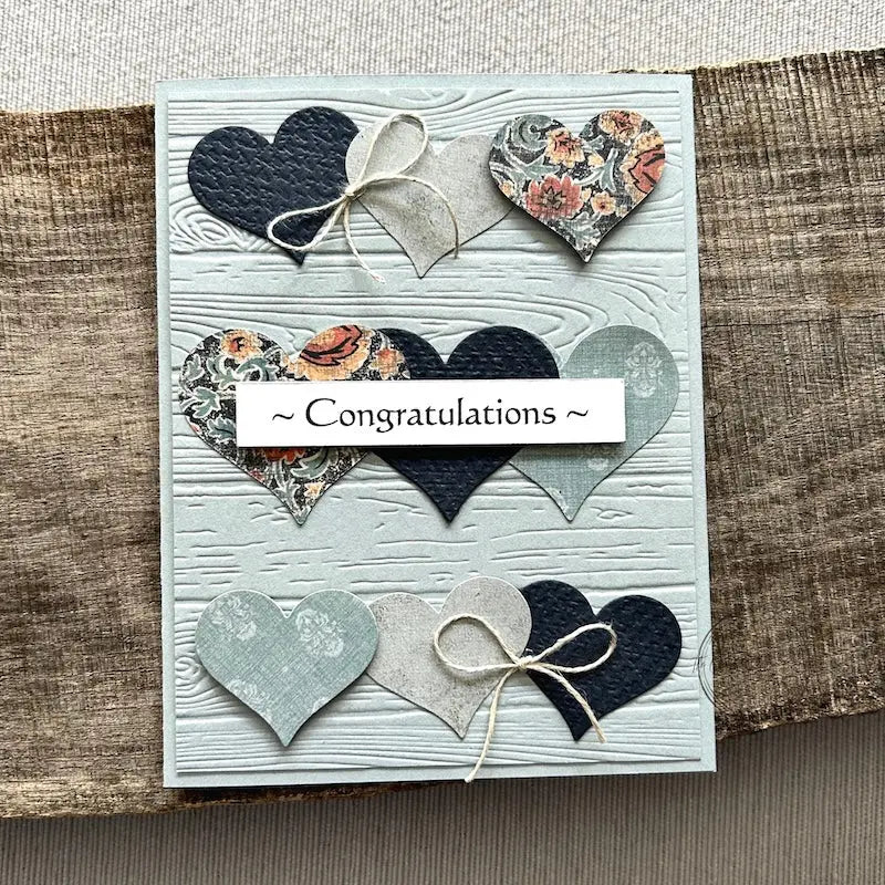 A finished card, from this card making kit, sitting on a wooden board.