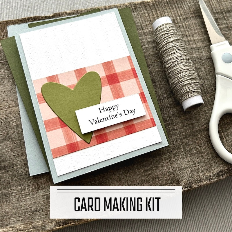 A classroom Valentines kit for kids. A finished valentine is sitting on blank cards with a roll of twine and scissors.