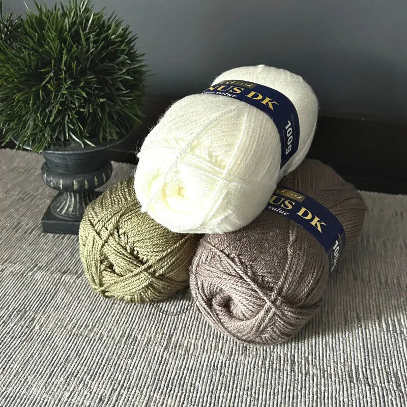 The 3 (out of 5) balls of yarn, that come in this crochet kit, are sitting on a table.