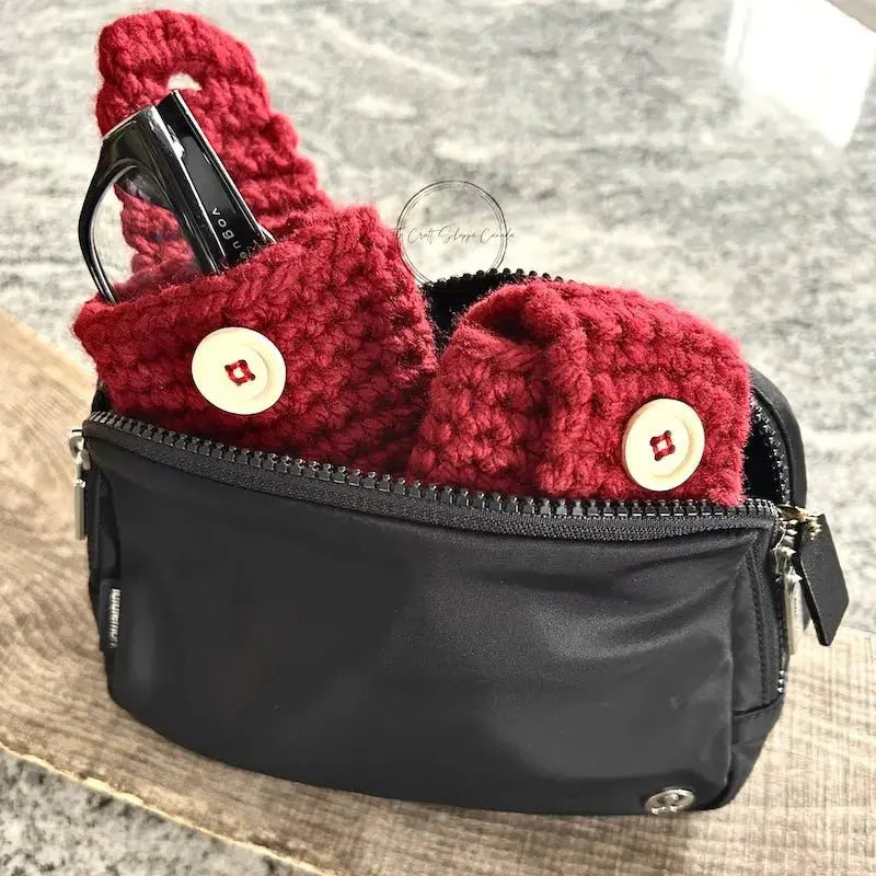 The accessory cases, made from this crochet pattern, are sitting in a purse with a pair of glasses poking out of the case.