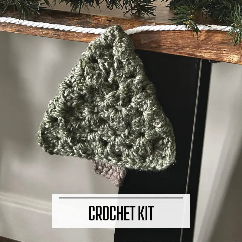 A crochet kit for a Christmas tree garland for your fireplace mantle. The finished garland is hanging over a table.
