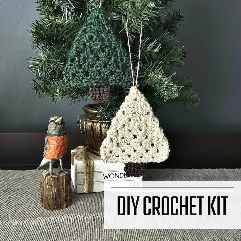 A DIY crochet kit for Christmas Tree Ornaments. The ornaments are hanging on Christmas tree, on a buffet, with a spring bird beside it.