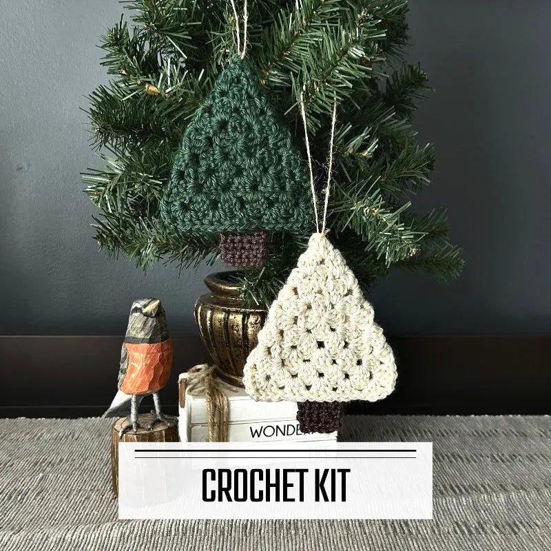 A DIY crochet kit for Christmas Tree Ornaments. The ornaments are hanging on Christmas tree, on a buffet, with a spring bird beside it.
