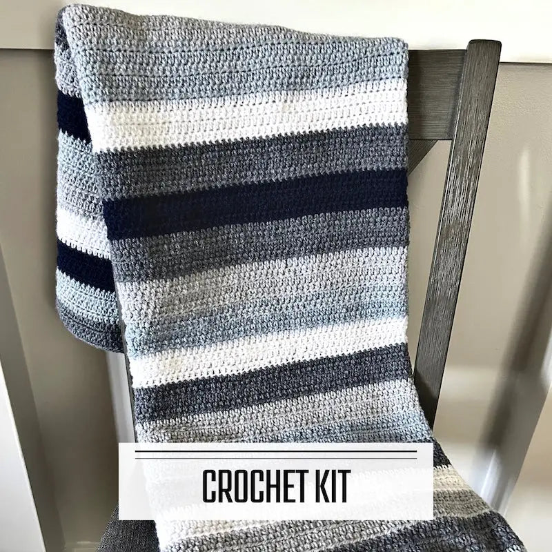 A crochet kit for a couch throw blanket. The finished blanket is lying over a chair.