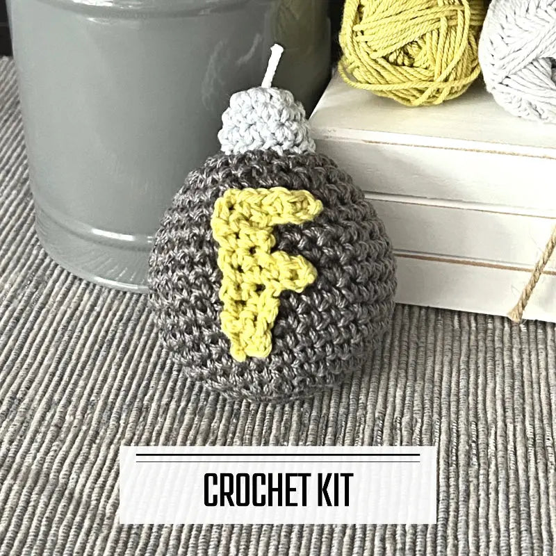 A DIY crochet kit for an amigurumi plush F bomb. The F bomb is sitting on a table with yarn on a wooden board.