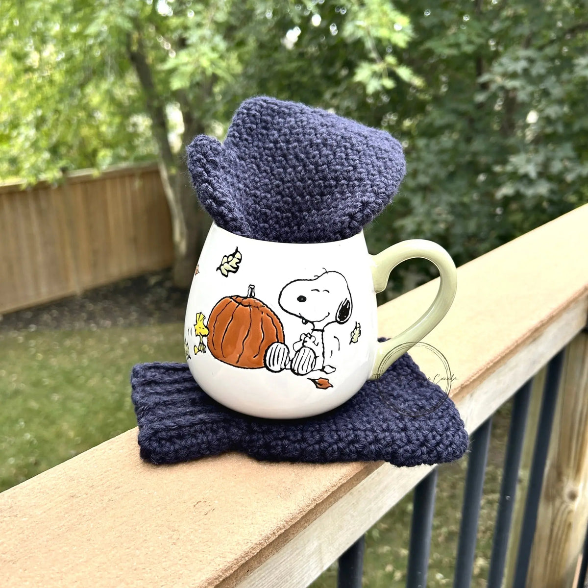 The mittens, made from this crochet kit, sitting in a mug on a ledge.