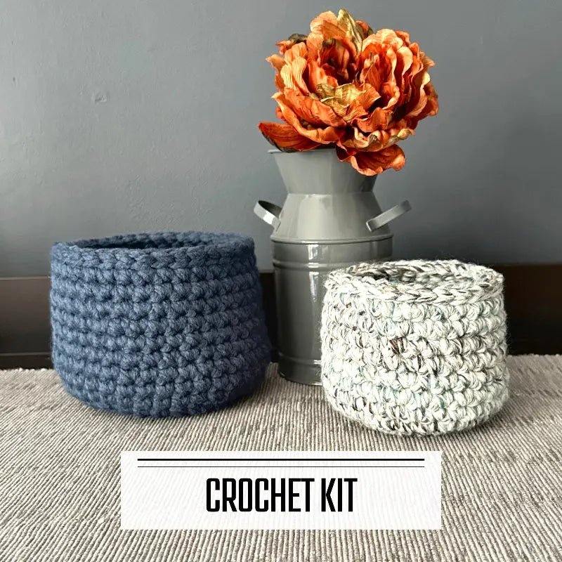 A crochet kit for a set of 2 storage baskets. The finished baskets are sitting on a table.
