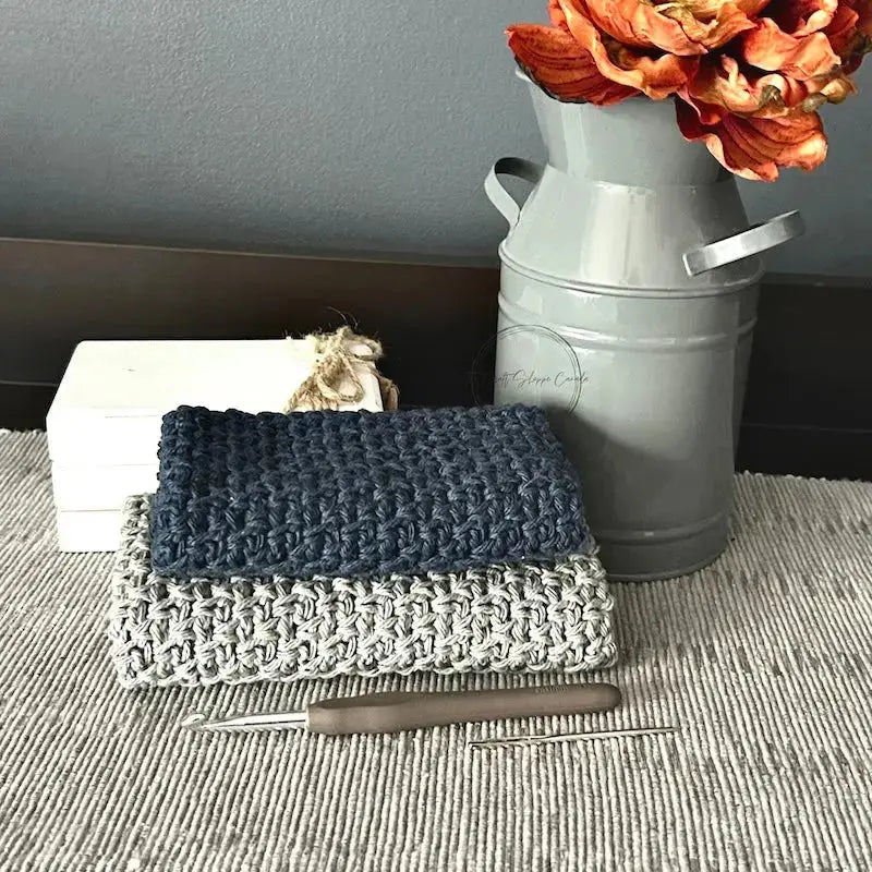 The finished washcloths, made from this crochet kit, are lying on a table board with a crochet hook.