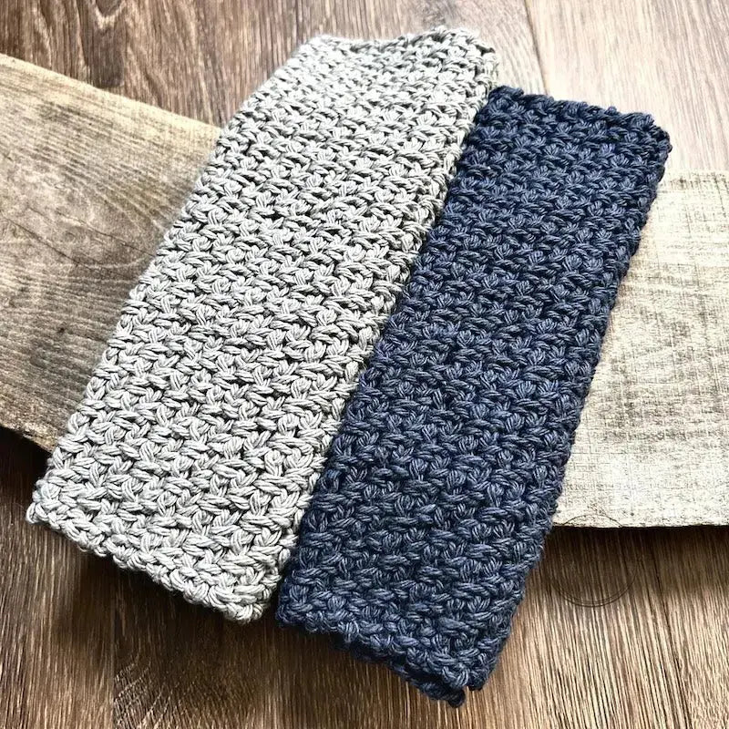 A close up of the finished washcloths, made from this crochet kit, lying over a wooden board.